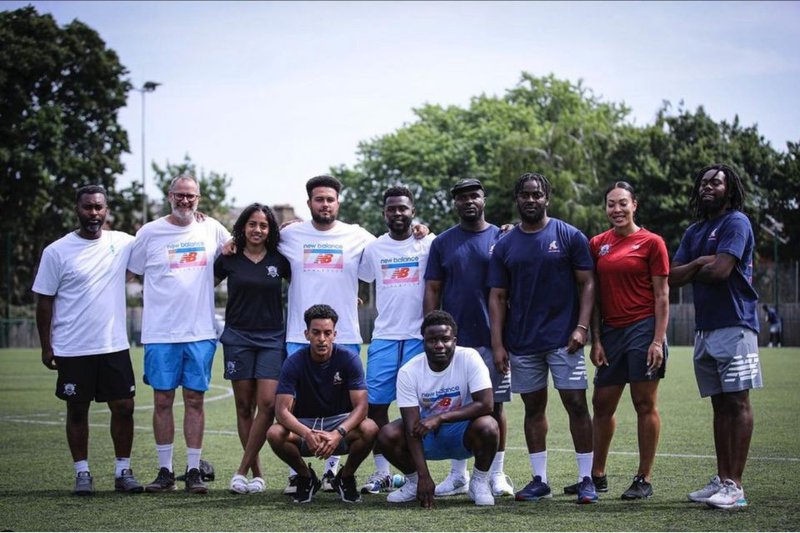 The Palma Foundation team at the 2022 summer camp. 12 adults in sports kit standing with linked arms on a training pitch.