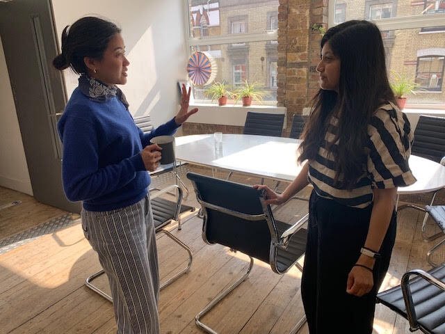 Two colleagues standing and talking together informally in the Unboxed office